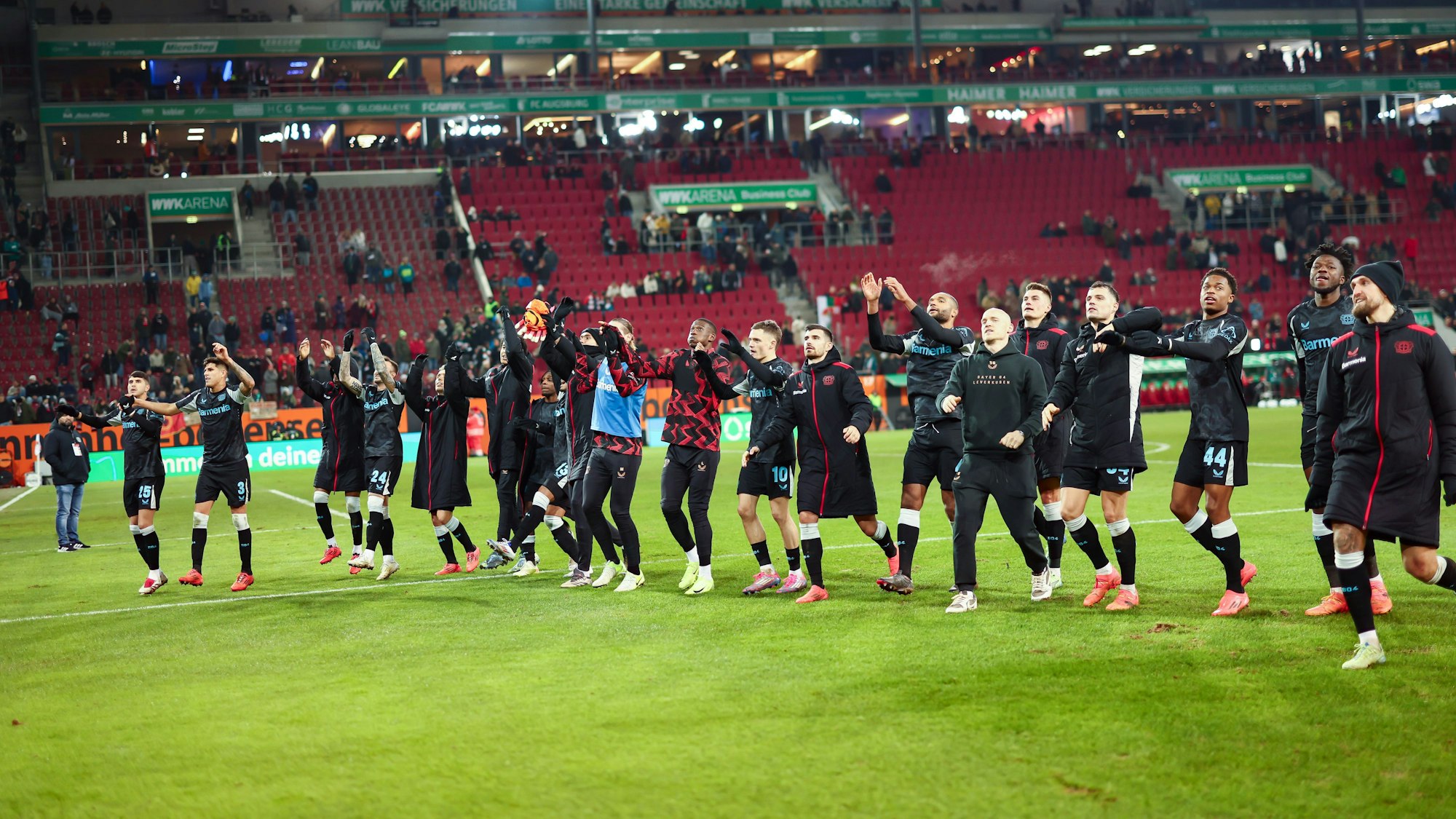 14.12.2024, Bayern, Augsburg: Fußball: Bundesliga, FC Augsburg - Bayer Leverkusen, 14. Spieltag, WWK-Arena. Das Team von Bayer 04 Leverkusen jubelt nach dem Spiel mit den Fans. Foto: Daniel Löb/dpa - WICHTIGER HINWEIS: Gemäß den Vorgaben der DFL Deutsche Fußball Liga bzw. des DFB Deutscher Fußball-Bund ist es untersagt, in dem Stadion und/oder vom Spiel angefertigte Fotoaufnahmen in Form von Sequenzbildern und/oder videoähnlichen Fotostrecken zu verwerten bzw. verwerten zu lassen. +++ dpa-Bildfunk +++