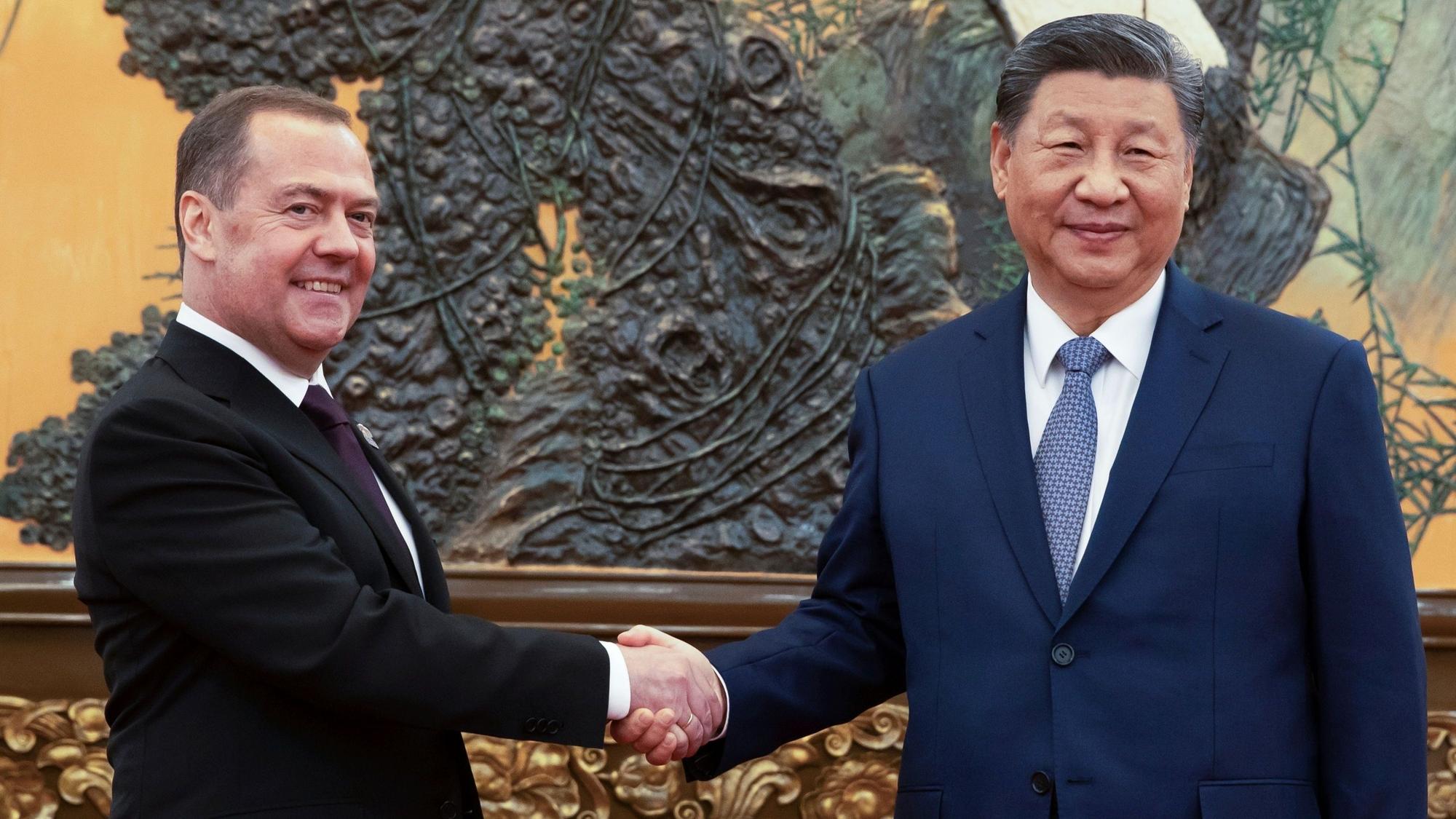 12.12.2024, China, Peking: Der stellvertretende Vorsitzende des russischen Sicherheitsrates und Chef der Partei "Einiges Russland", Dmitri Medwedew (l) und der chinesische Präsident Xi Jinping geben sich während ihres Treffens die Hände. Foto: Ekaterina Shtukina/Pool Sputnik/AP/dpa +++ dpa-Bildfunk +++