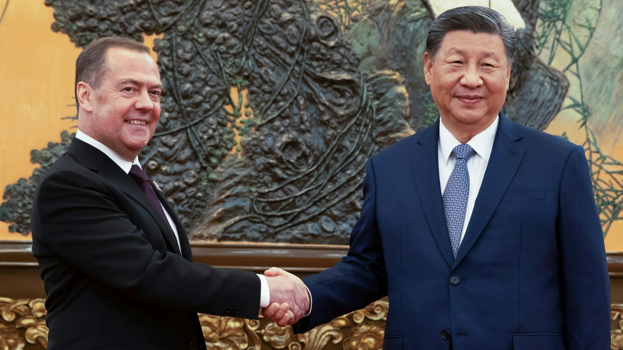 12.12.2024, China, Peking: Der stellvertretende Vorsitzende des russischen Sicherheitsrates und Chef der Partei "Einiges Russland", Dmitri Medwedew (l) und der chinesische Präsident Xi Jinping geben sich während ihres Treffens die Hände. Foto: Ekaterina Shtukina/Pool Sputnik/AP/dpa +++ dpa-Bildfunk +++