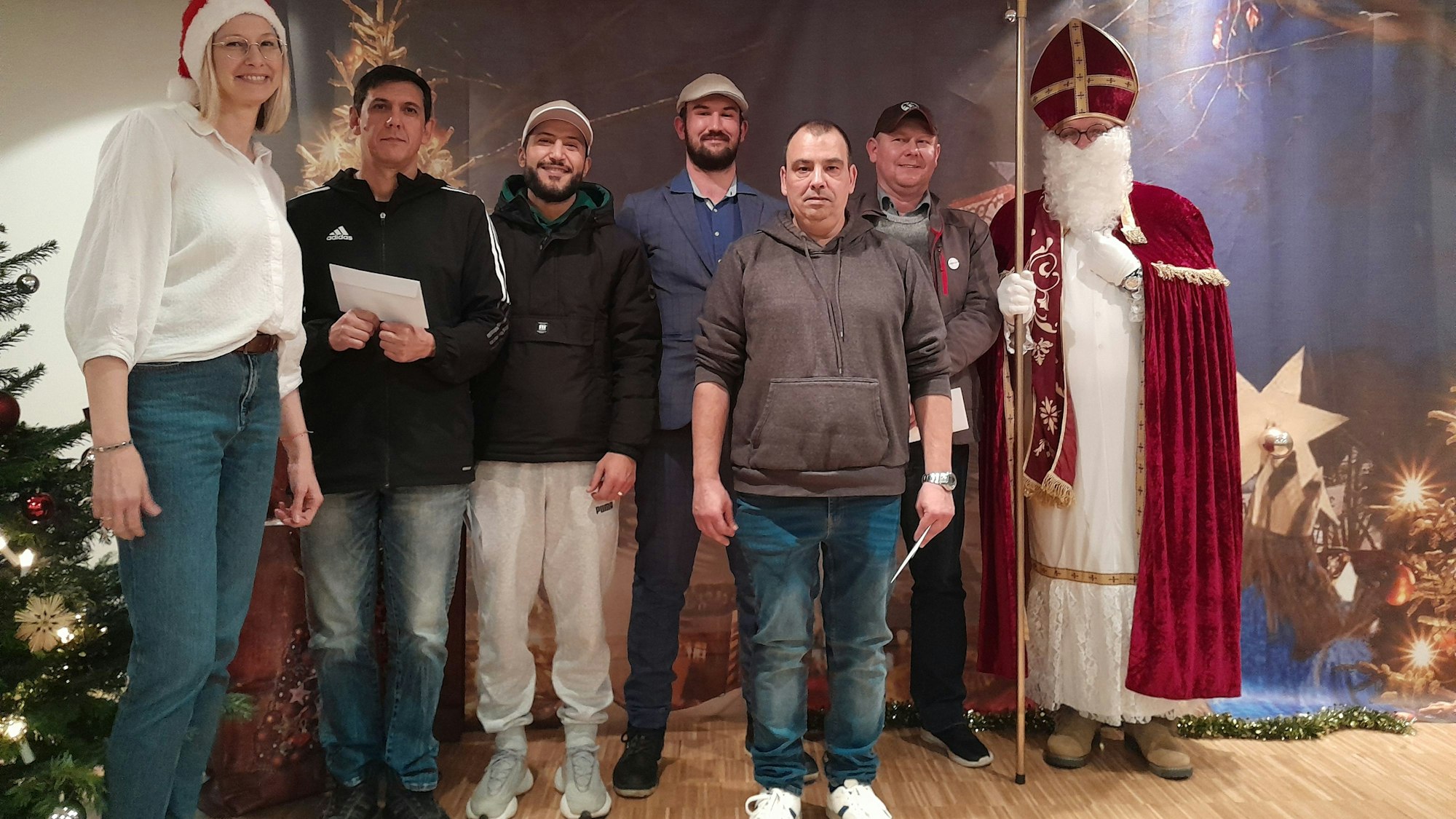 Fünf Männer, ein Mann im Nikolauskostüm und eine Frau stehen auf einer Bühne