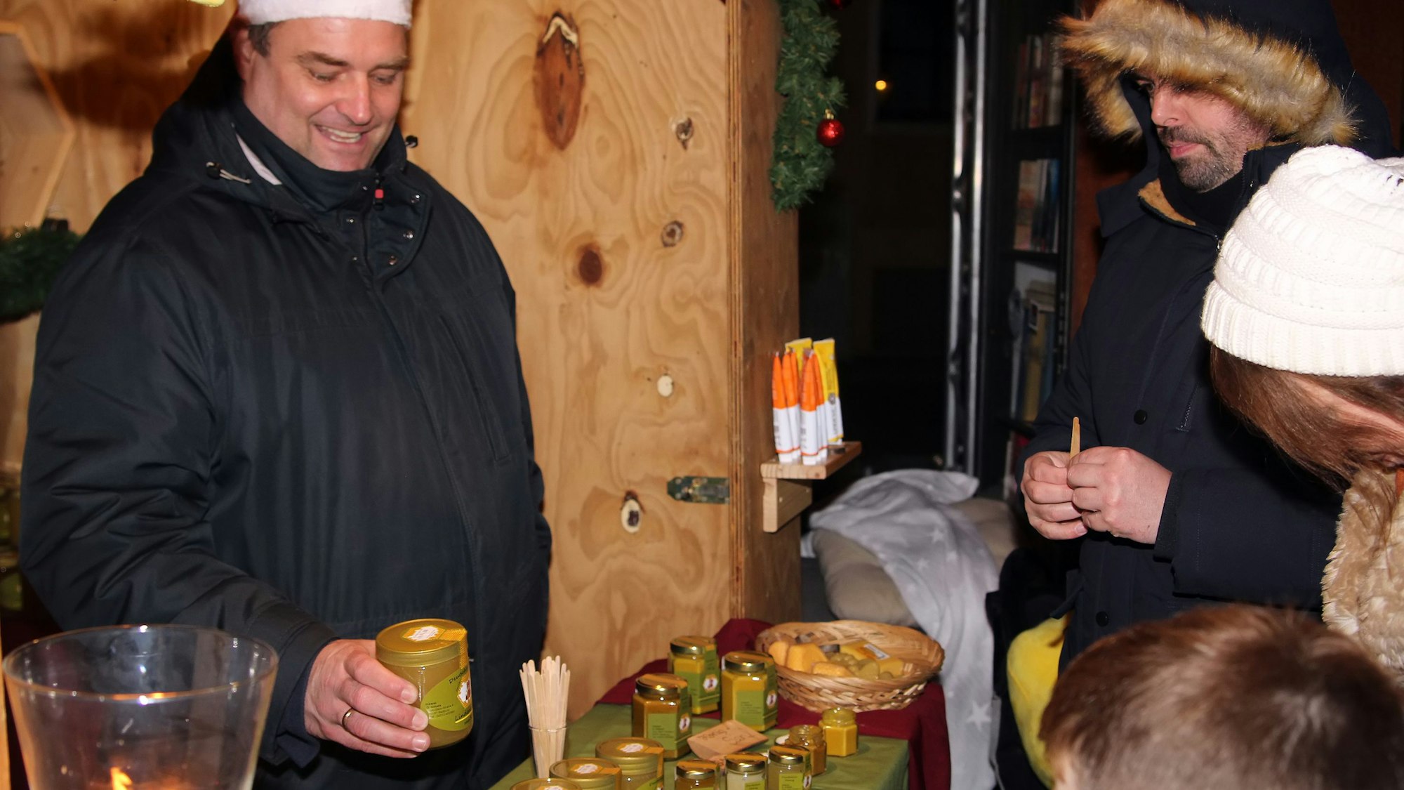 Auf dem Bild ist der Stand eines Imkers mit Besuchern zu sehen.
