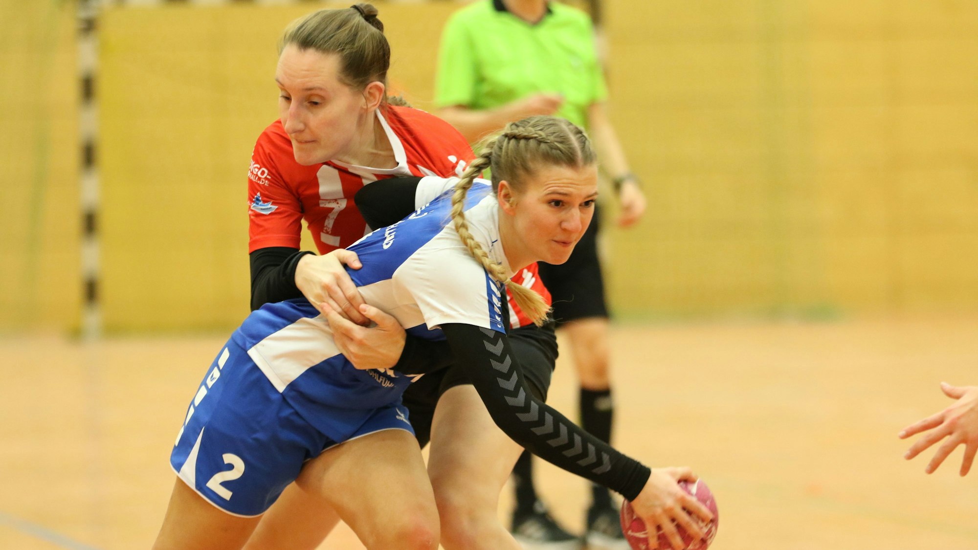 Eine Handballspielerin umschließt die Gegnerin, die den Ball hat, mit beiden Armen.