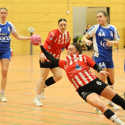 Eine Handballerin liegt beim Wurf schräg in der Luft. Sie wurde allerdings unsanft gestoppt.