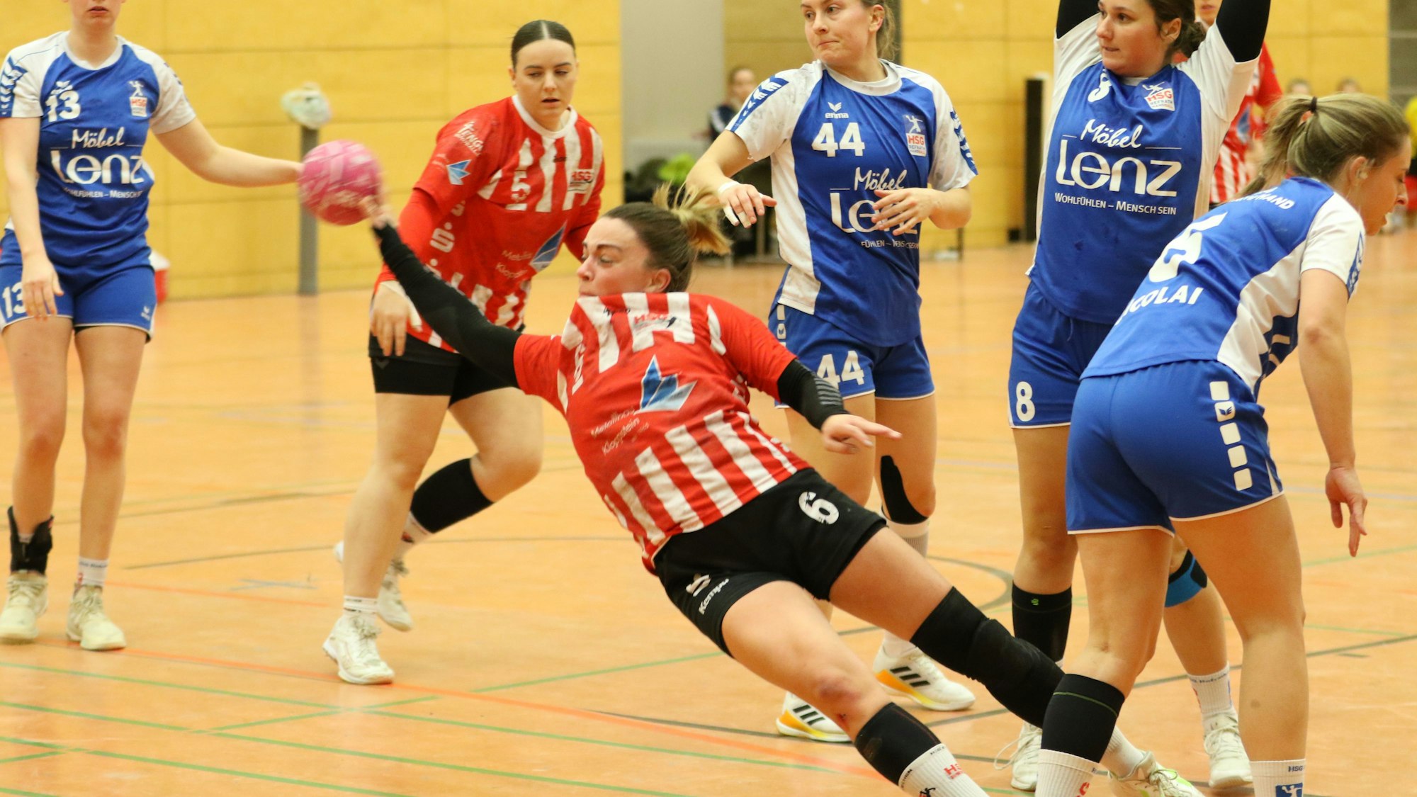 Eine Handballerin liegt beim Wurf schräg in der Luft. Sie wurde allerdings unsanft gestoppt.