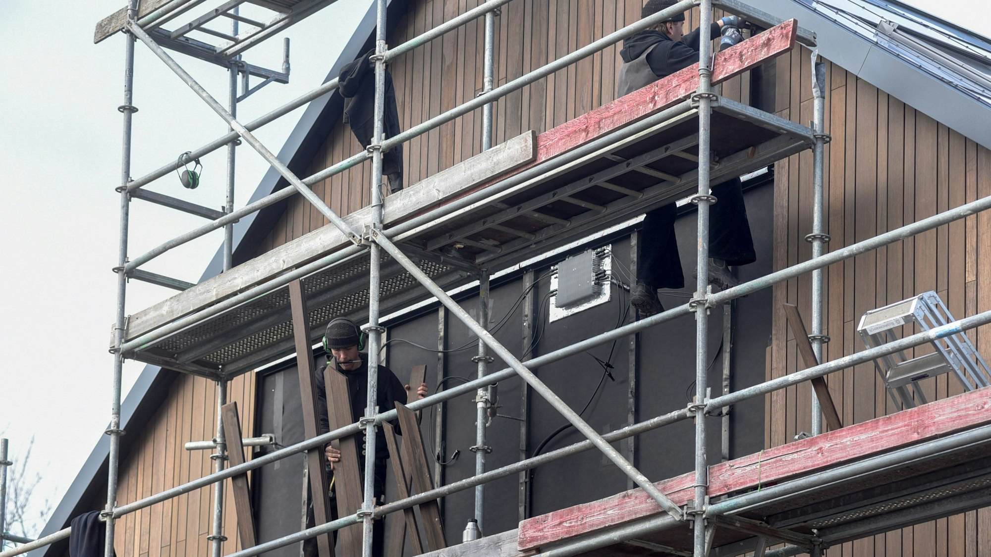 Auf dem Bild ist ein eingerüstetes Haus mit Handwerkern zu sehen.
