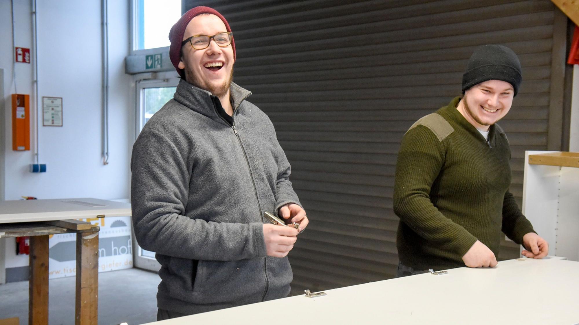 Auf dem Bild sind zwei Handwerker in der Werkstatt zu sehen.