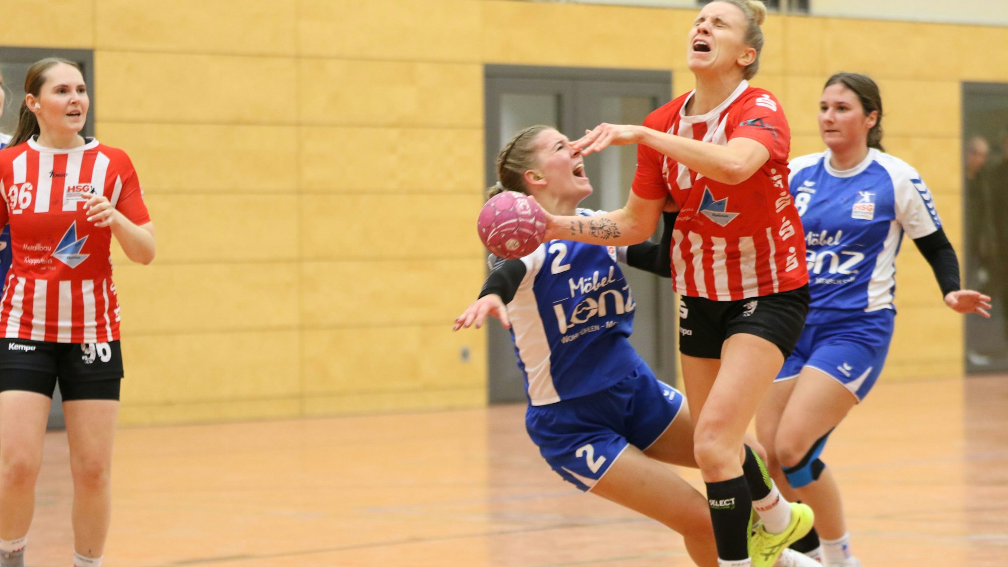 Beim Wurf wird eine Handballerin von der Gegnerin an den Beinen getroffen. Beide Frauen schreien.