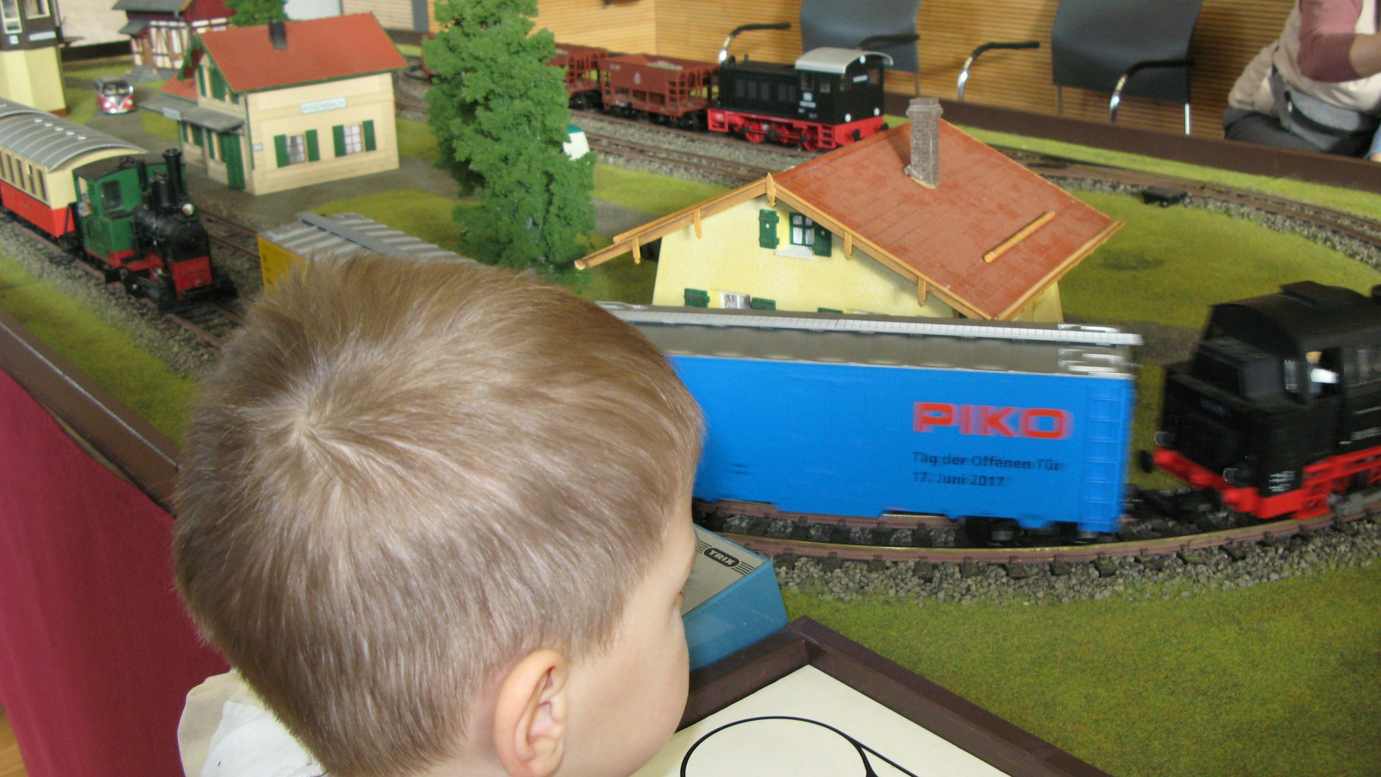 Ein Junge bedient den Trafo einer Modellbahnanlage, auf der ein Zug fährt.