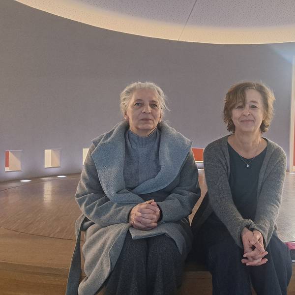 Zwei Frauen sitzen auf einer runden Holzbühne.