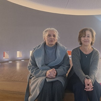 Zwei Frauen sitzen auf einer runden Holzbühne.