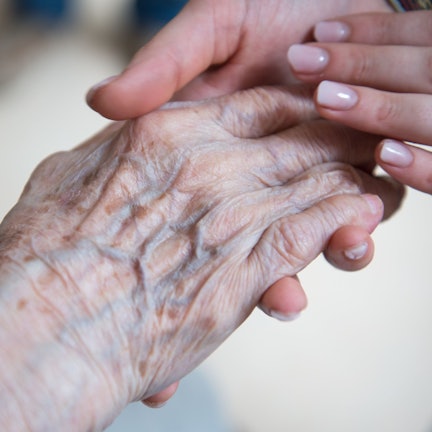 Eine jung Frau hält die Hand einer alten Frau.