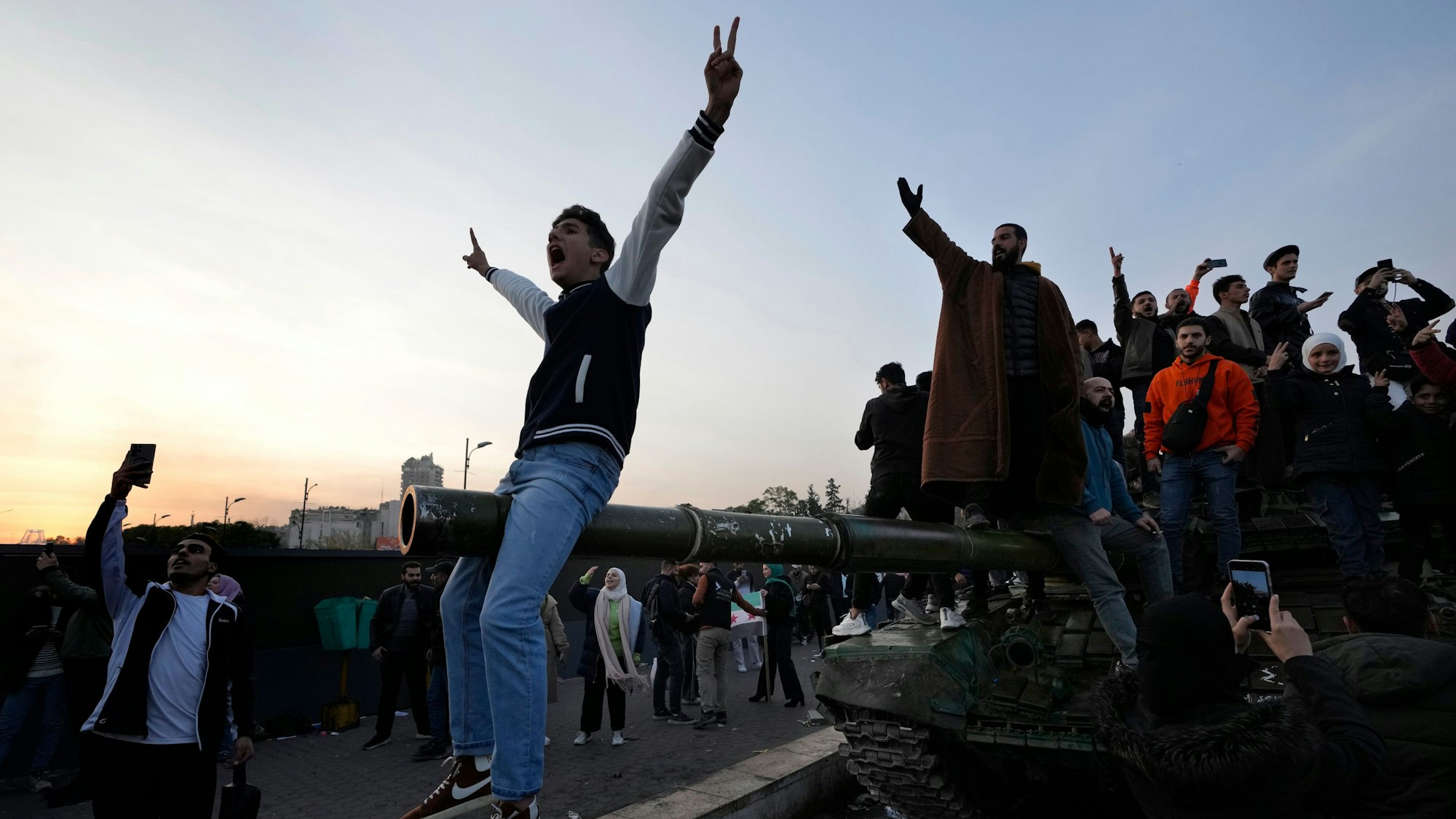 Syrische Bürger stehen auf einem Panzer der Regierungstruppen, und feiern die Übernahme der Stadt durch die Aufständischen.