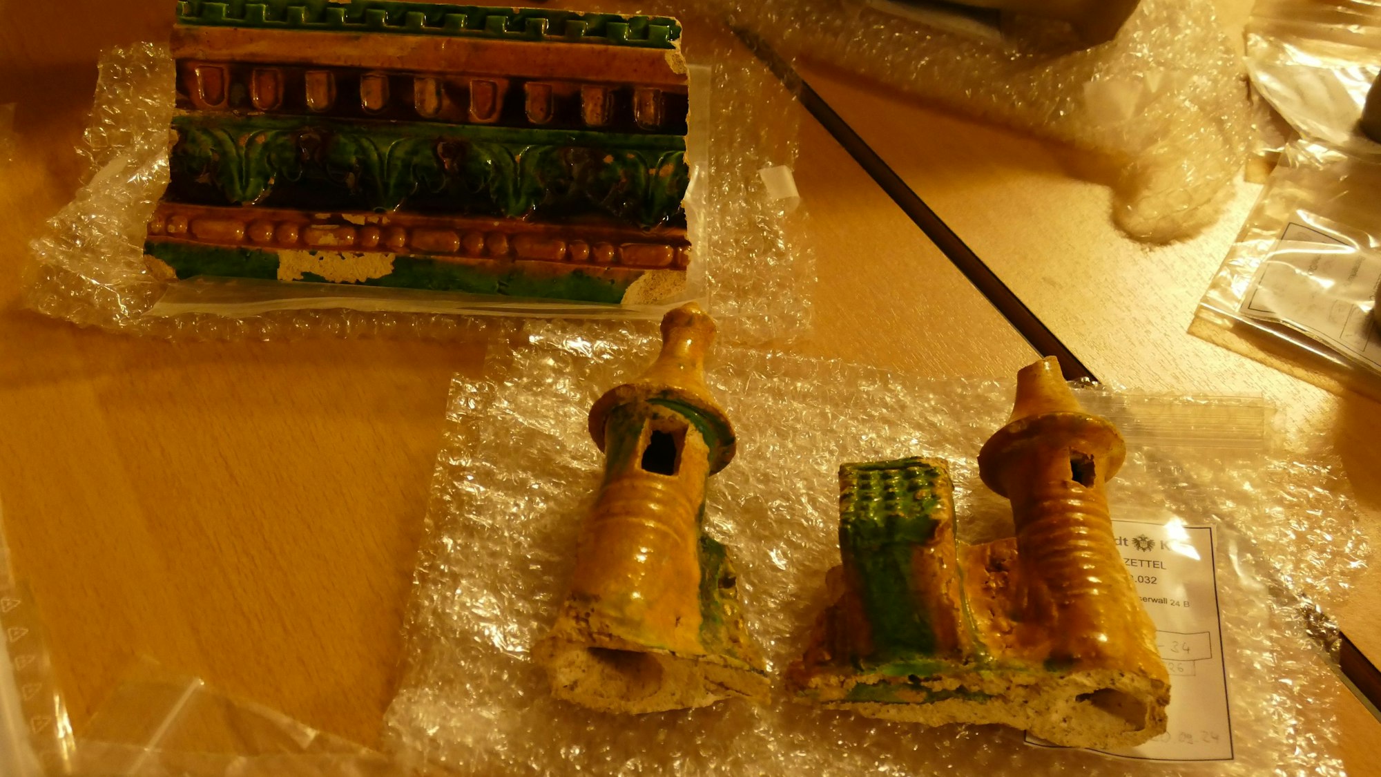 Auf einem Tisch liegen turmförmige und bunt bemalte Keramikbruchstücke.