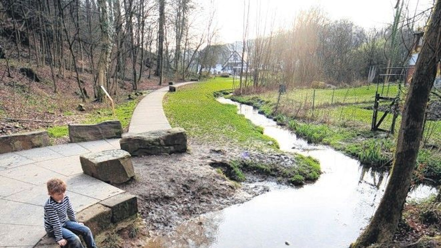 Ein Kind sitzt an der Quelle der Strunde.