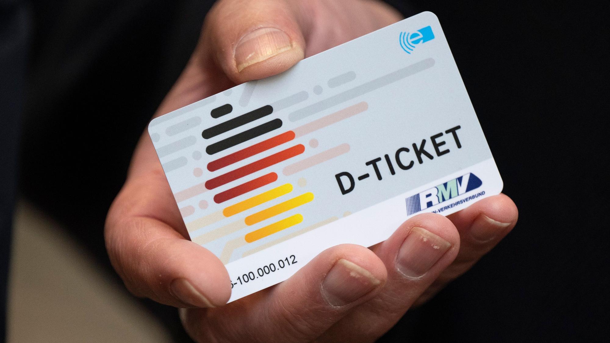 Eine Hand hält ein Deutschlandticket. (Symbolbild)