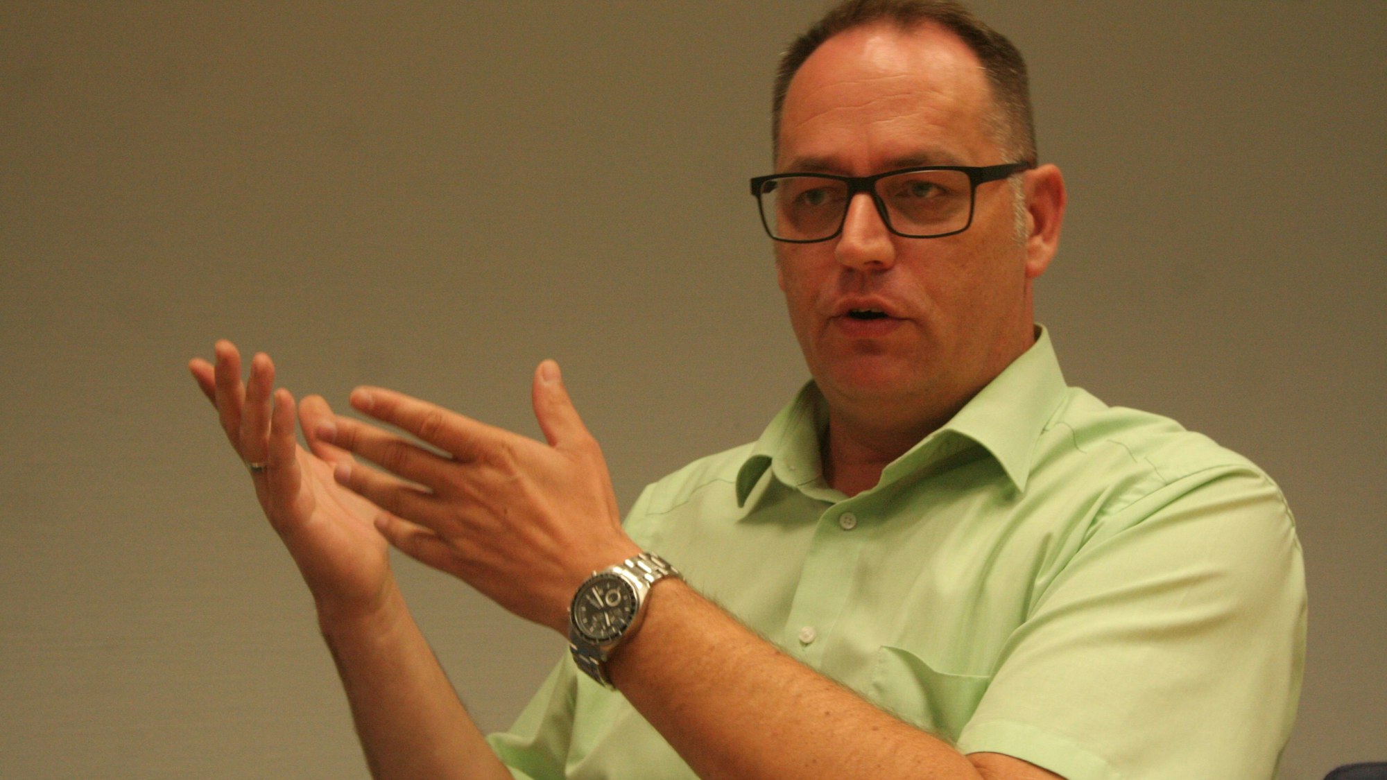 Auf dem Foto ist ein Mann in einem kurzärmeligen Hemd zu sehen.