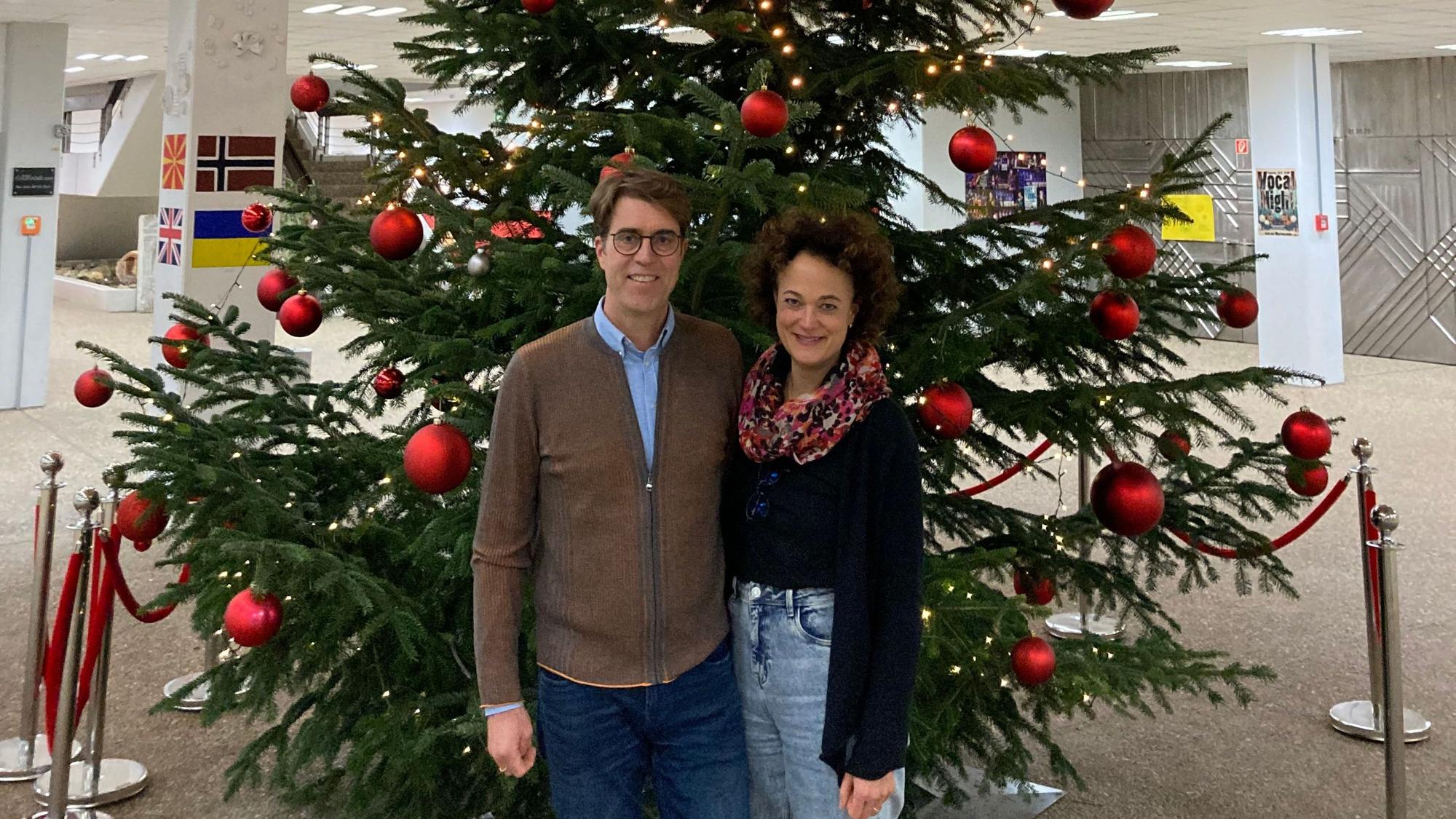 Michael und Barbara Luke stehen neben einem großen, mit roten Kugeln geschmückten Weihnachtsbaum.
