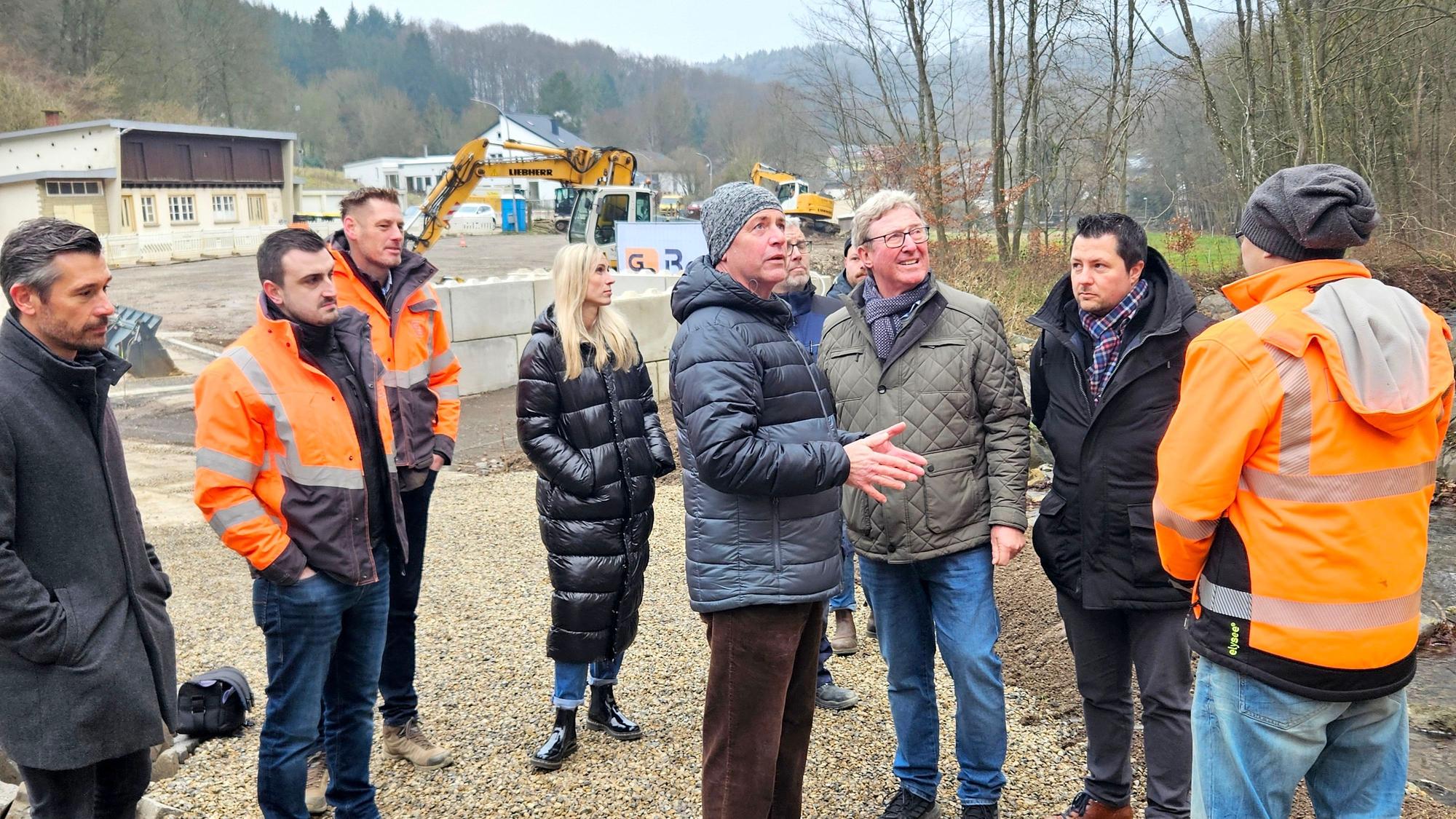 Vertreter des Hermann-Josef-Hauses, des Planungsbüros und der Baufirma stehen mit Hermann-Josef Esser (5.v.l.) und Manfred Poth (3.v.r.) am Gillesbach.