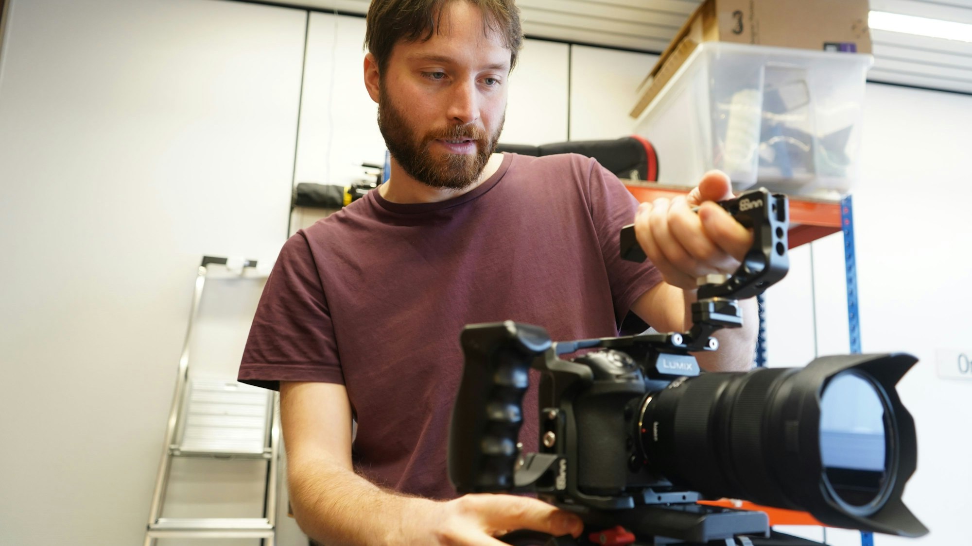 Das Foto zeigt einen jungen Mann mit einer Kamera in der Hand.