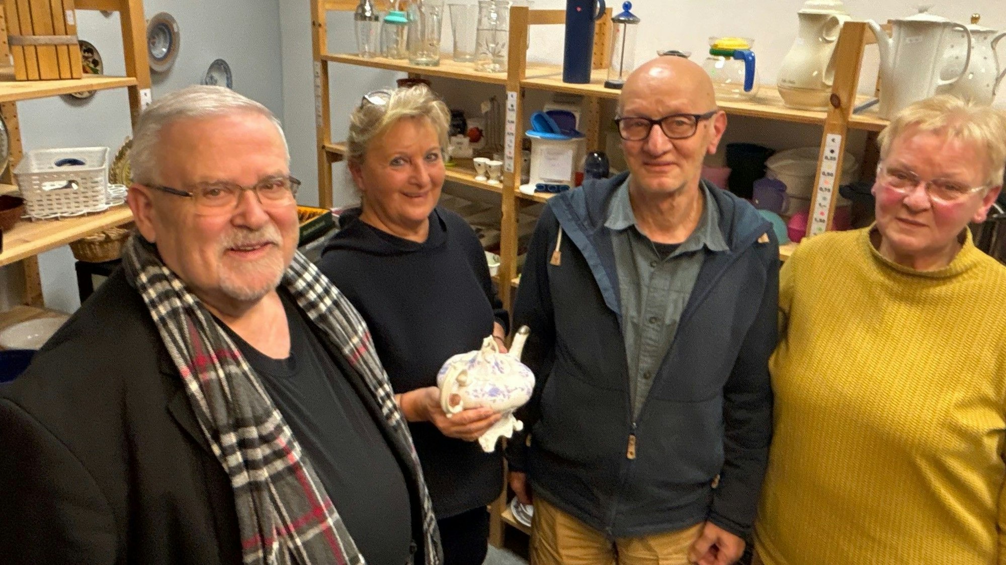 Auf dem Bild sind zwei Frauen und zwei Männer vor einem Regal in dem Sozialkaufhaus zu sehen.