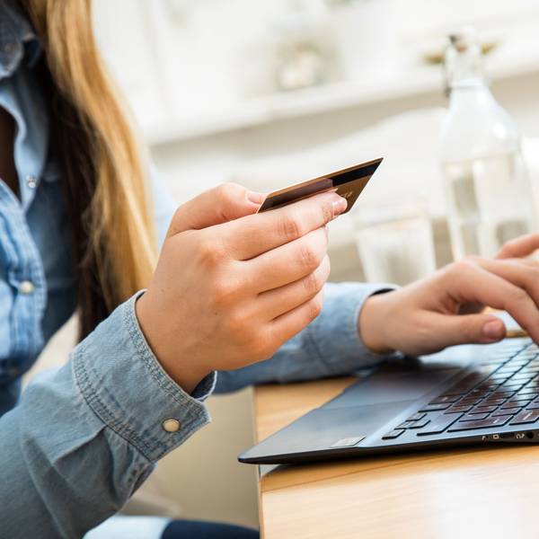 Eine Frau sitzt mit einer Kreditkarte am Laptop.