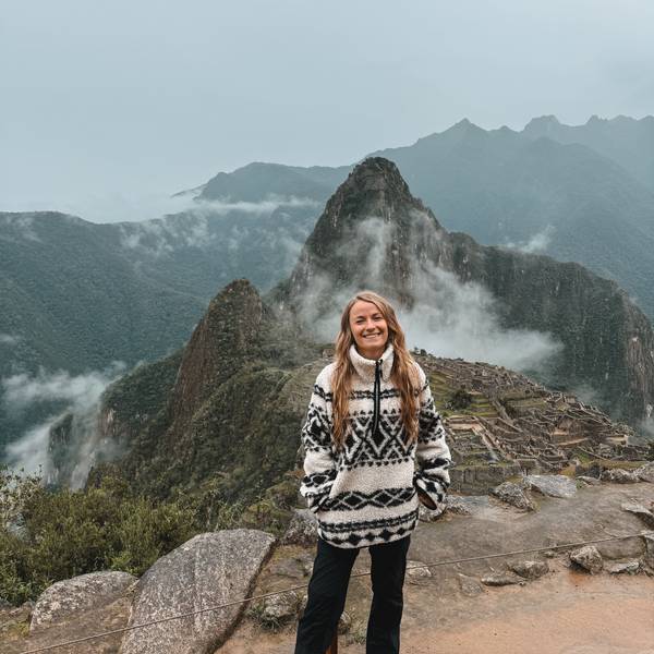 Jil Eileen Füngeling steht auf einer Anhöhe, im Hintergrund ist die Ruinenstadt Machu Picchu zu sehen.