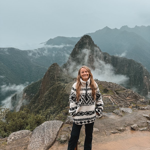 Jil Eileen Füngeling steht auf einer Anhöhe, im Hintergrund ist die Ruinenstadt Machu Picchu zu sehen.