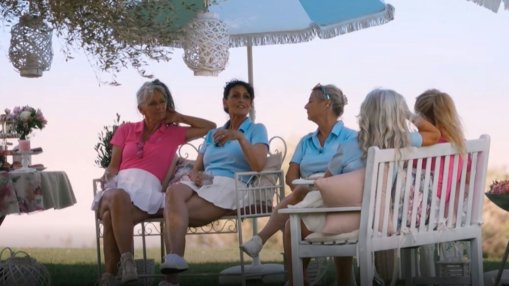 Sabine (l.) geht in der Frauengruppe beim Date etwas unter. Vier weitere Frauen sitzen auf Bänken im Kreis, unterhalten sich.