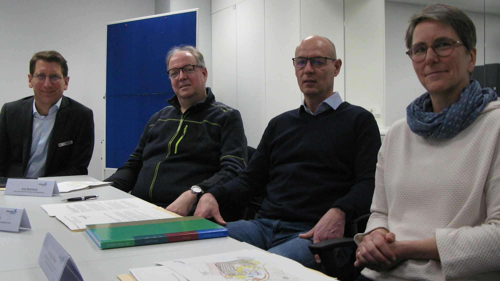 Drei Männer und eine Frau von der Kreisverwaltung an einem Tisch, auf dem schriftliche Unterlagen liegen.