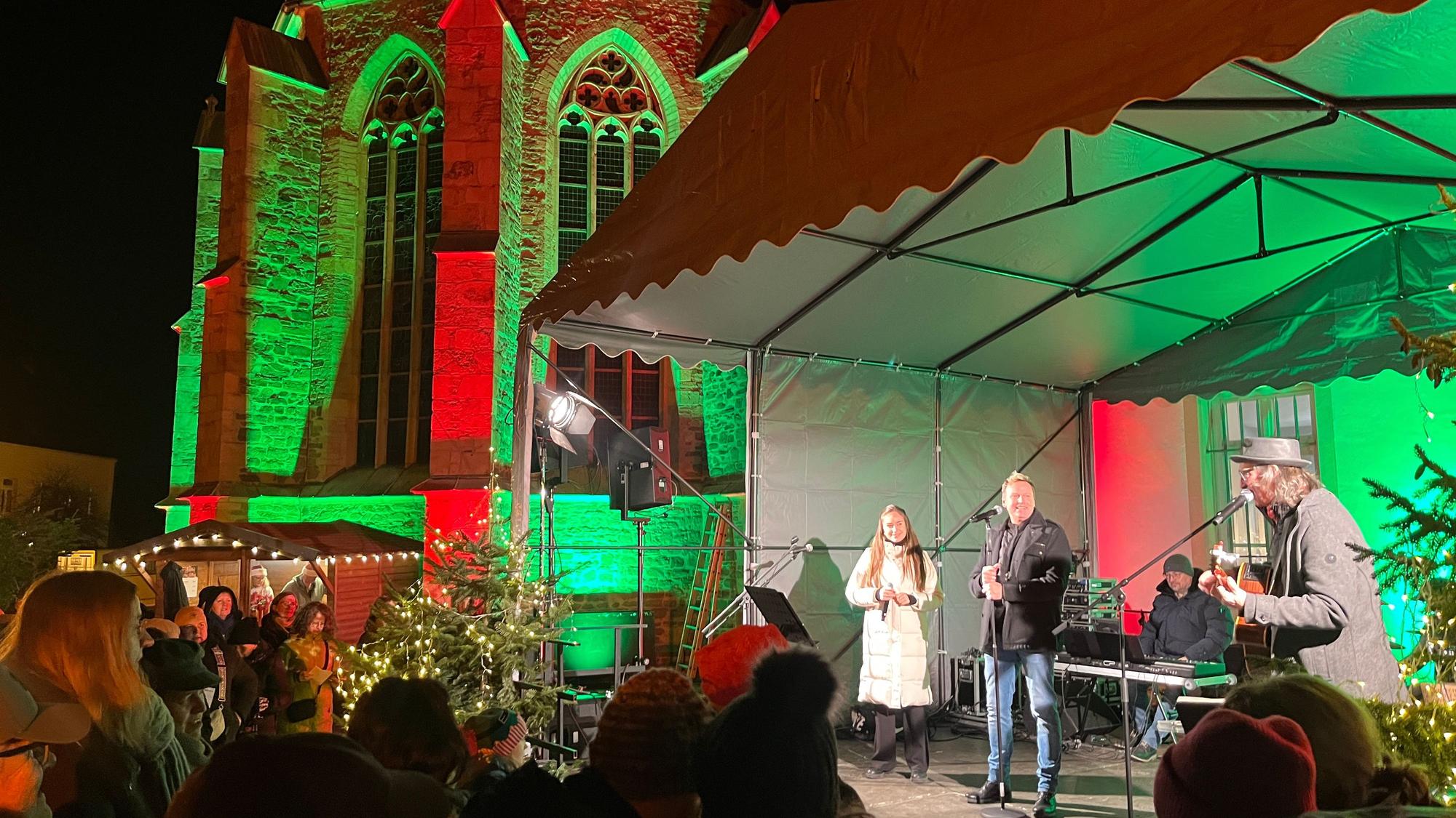 Eine Band steht auf einer Bühne vor einer beleuchteten Kirche.