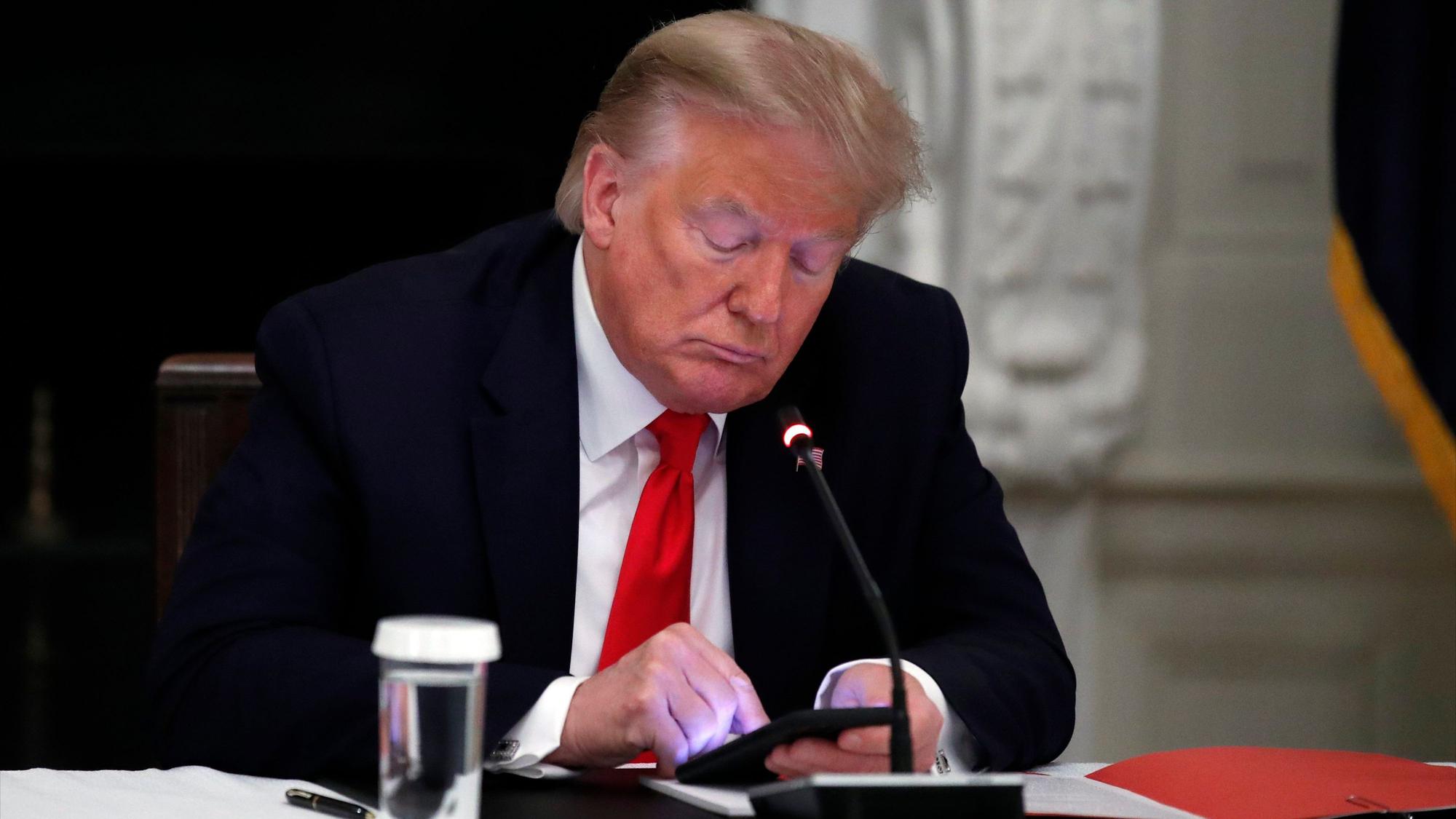 Während eines runden Tisches schaut Donald Trump auf sein Handy. (Archivbild)