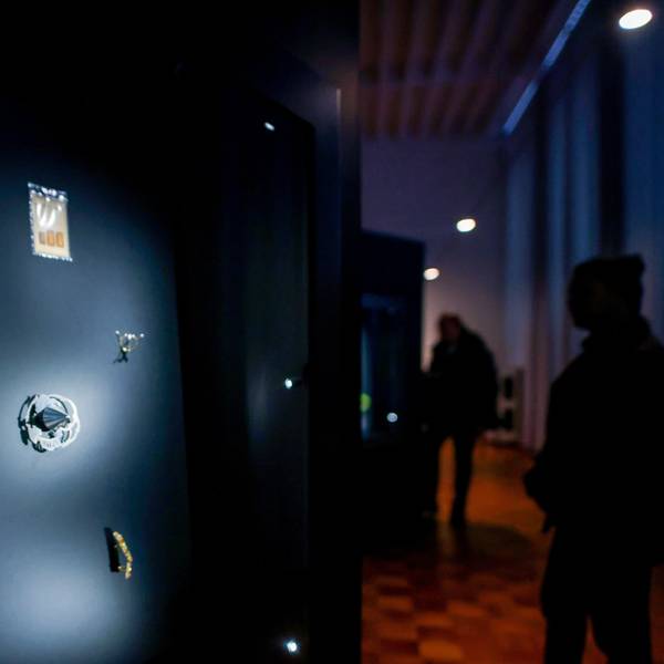 Das Bild zeigt eine erleuchtete Vitrine mit modernen Schmuckobjekten in den abgedunkelten Räumen des Museums für Angewandte Kunst in Köln.