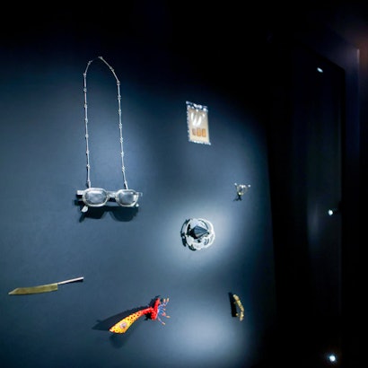 Das Bild zeigt eine erleuchtete Vitrine mit modernen Schmuckobjekten in den abgedunkelten Räumen des Museums für Angewandte Kunst in Köln.