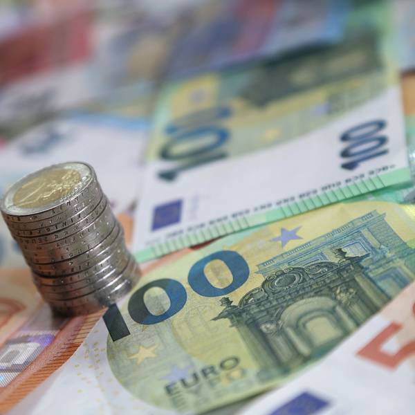 Ein Stapel mit Zwei-Euro-Münzen steht auf verschiedenen Euro-Banknoten.