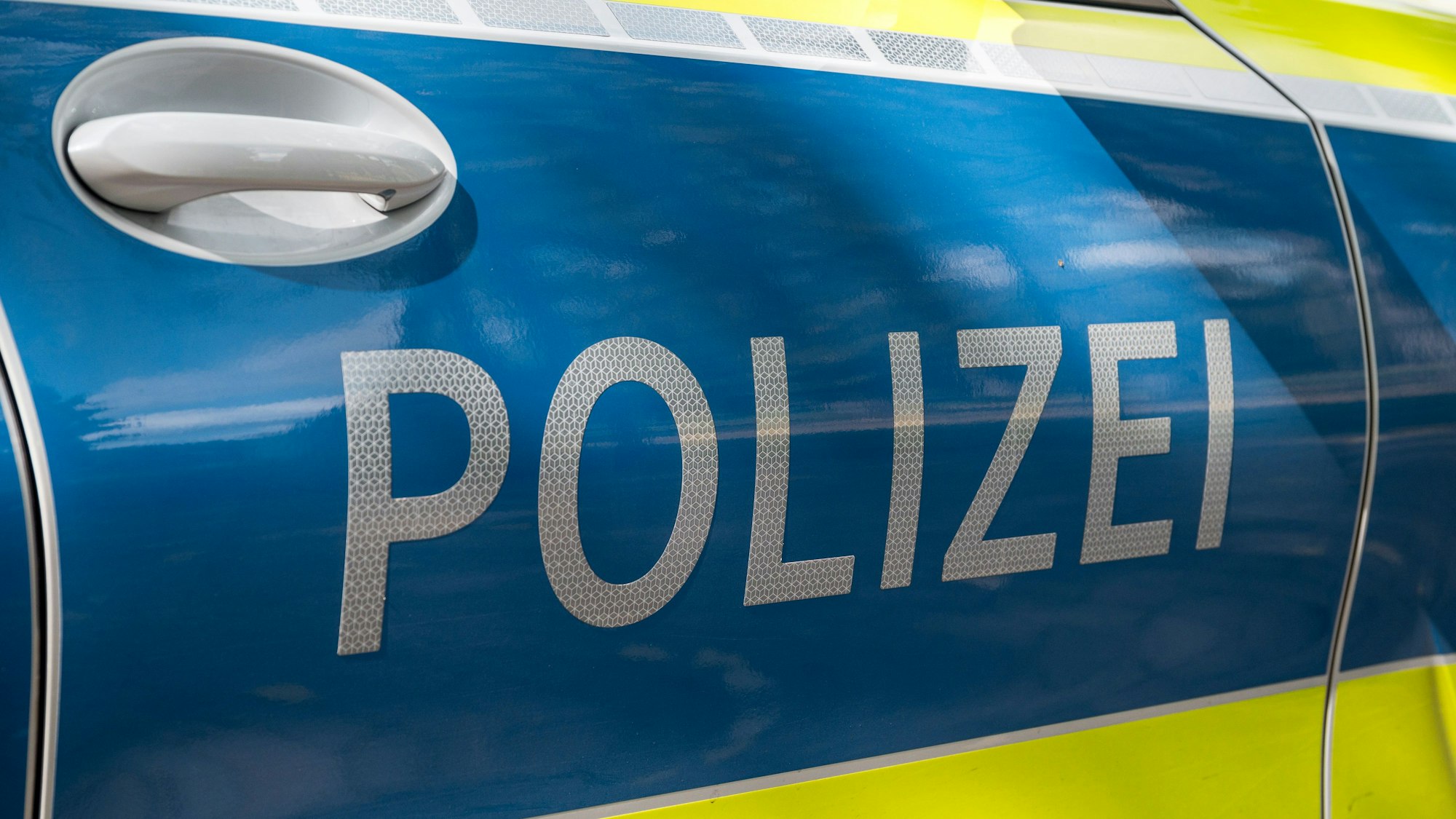 Auf einem Einsatzwagen ist der Schriftzug „Polizei“ zu lesen.