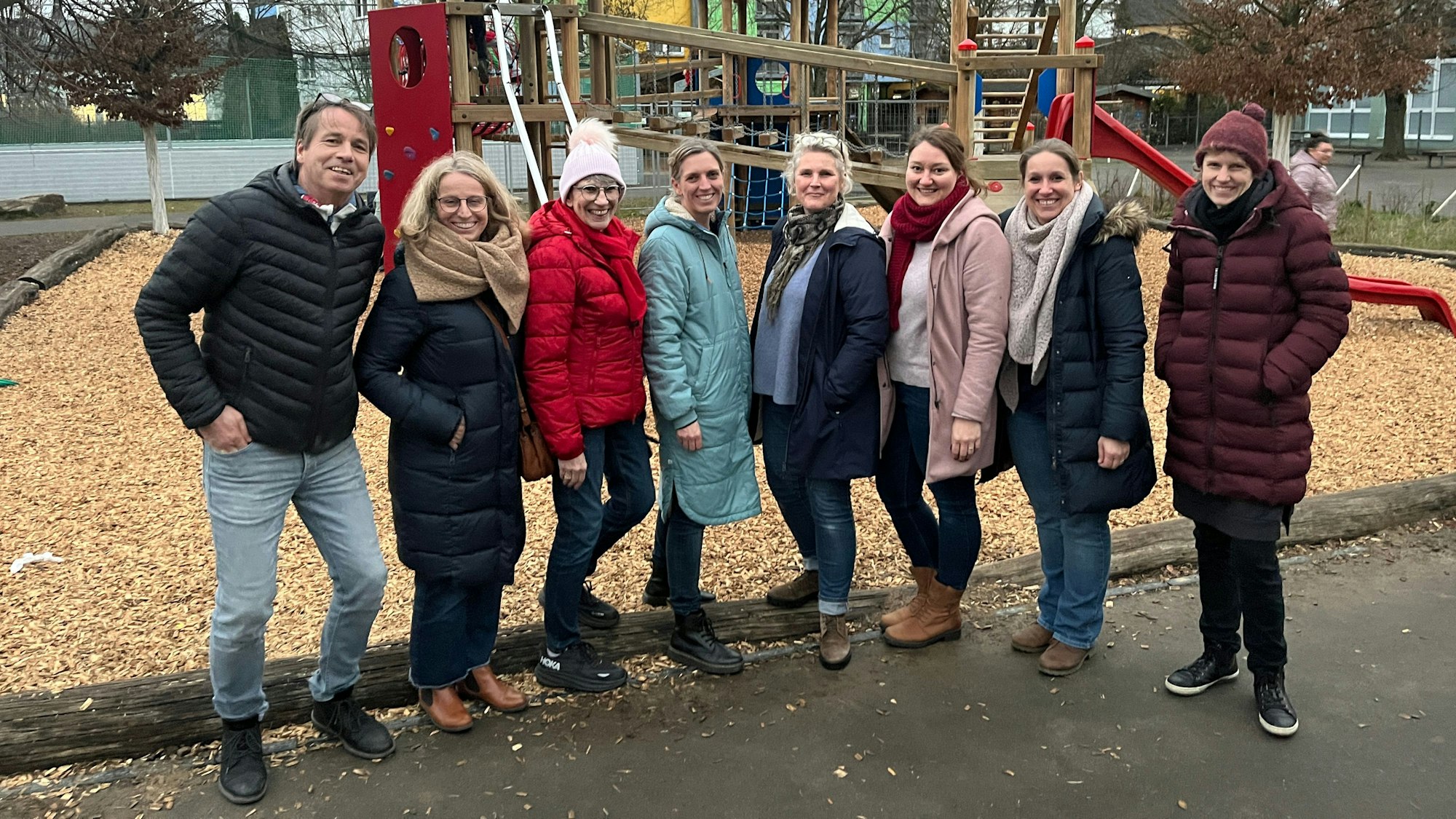 Acht Erwachsene stehen vor einem Spielgerät für Kinder.