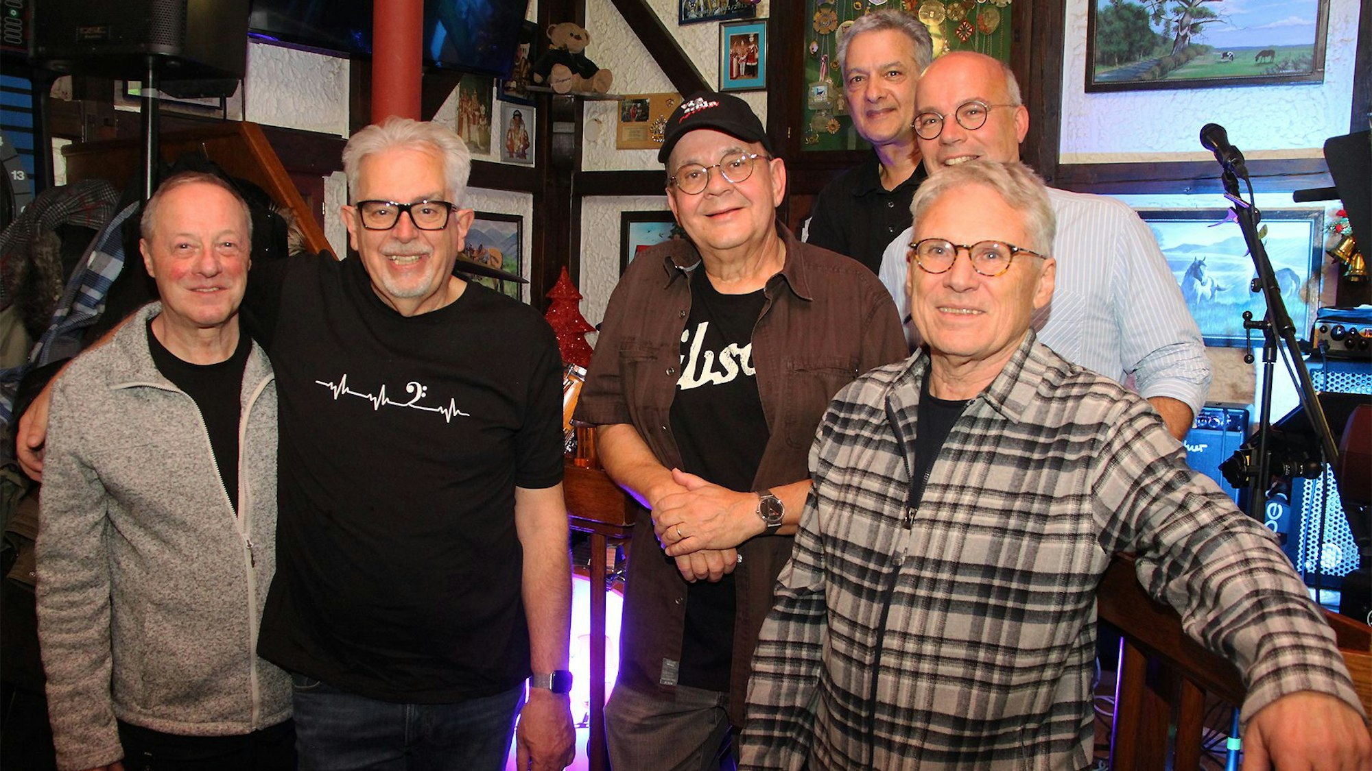 Sechs ältere Herren stehen zusammen und lachen in die Kamera.