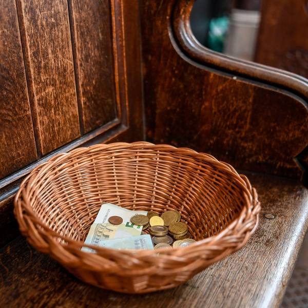 Ein Korb mit der Kollekte aus Geldscheinen und Münzen steht auf einer Kirchenbank (Symbolbild).