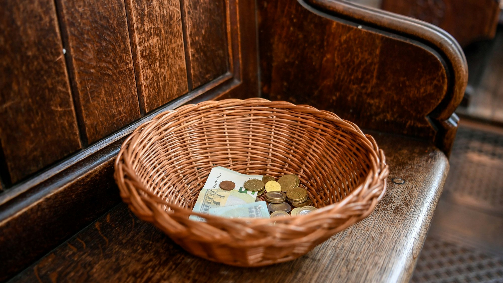 Ein Korb mit Geldscheinen und Münzen steht in einer Kirche.