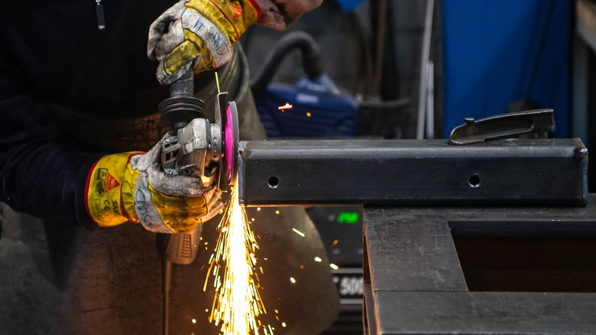 Das Bild zeigt einen Metallbauer, der eine Metallkonstruktion abschleift.