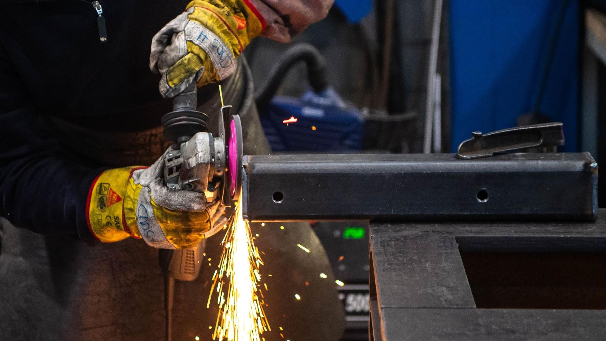 Das Symbolbild zeigt einen Metallbauer beim Bearbeiten eines Werkstücks.