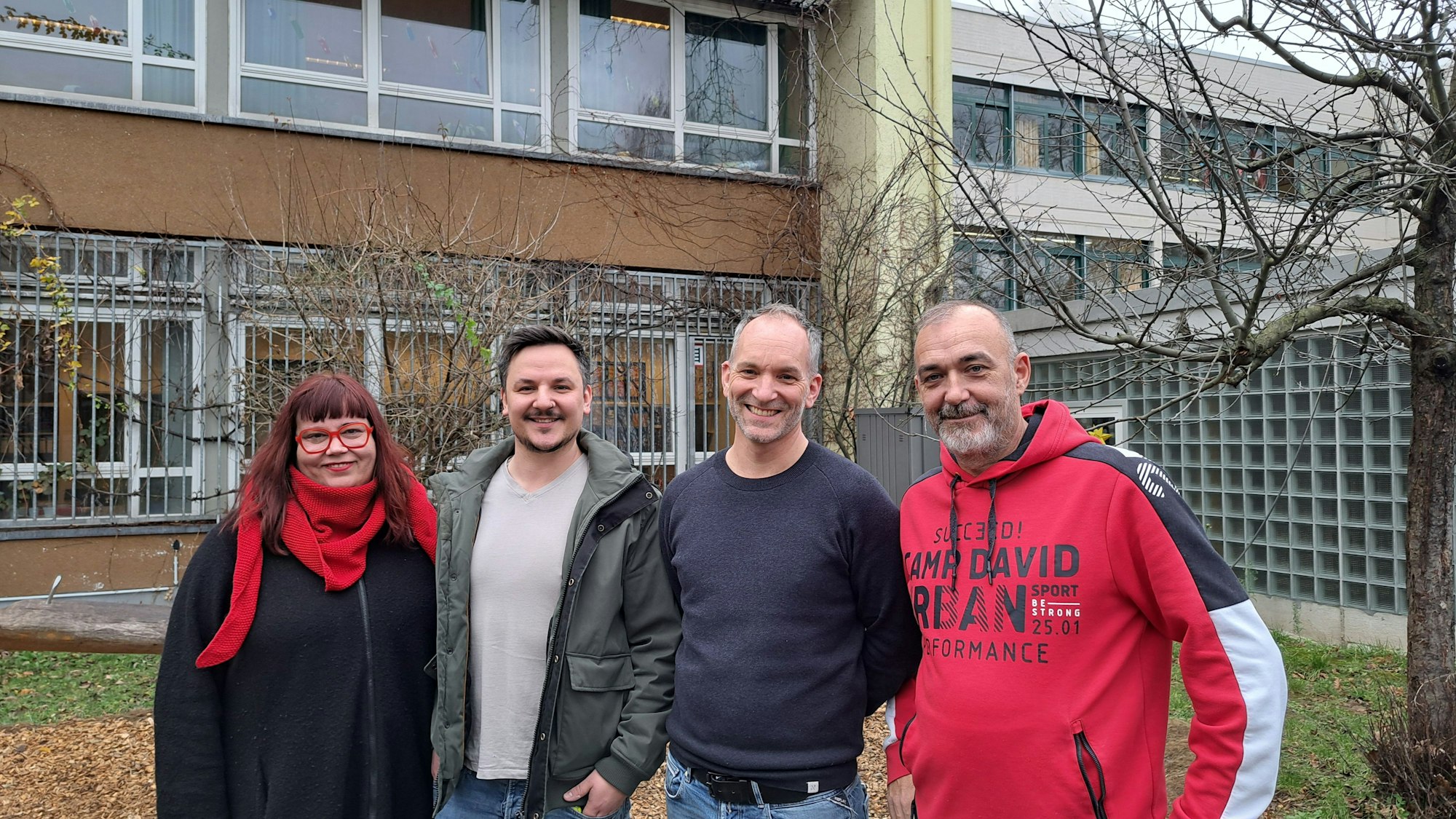 Vier Personen stehen vor einem Schulgebäude nebeneinander. v.l.: Sara Berthon, Konrektorin, Kai Wojtas, Koordinator des Familiengrundschulzentrums, Johannes Köper-Braun, Rektor und Guido Rosenbaum, Hausmeister