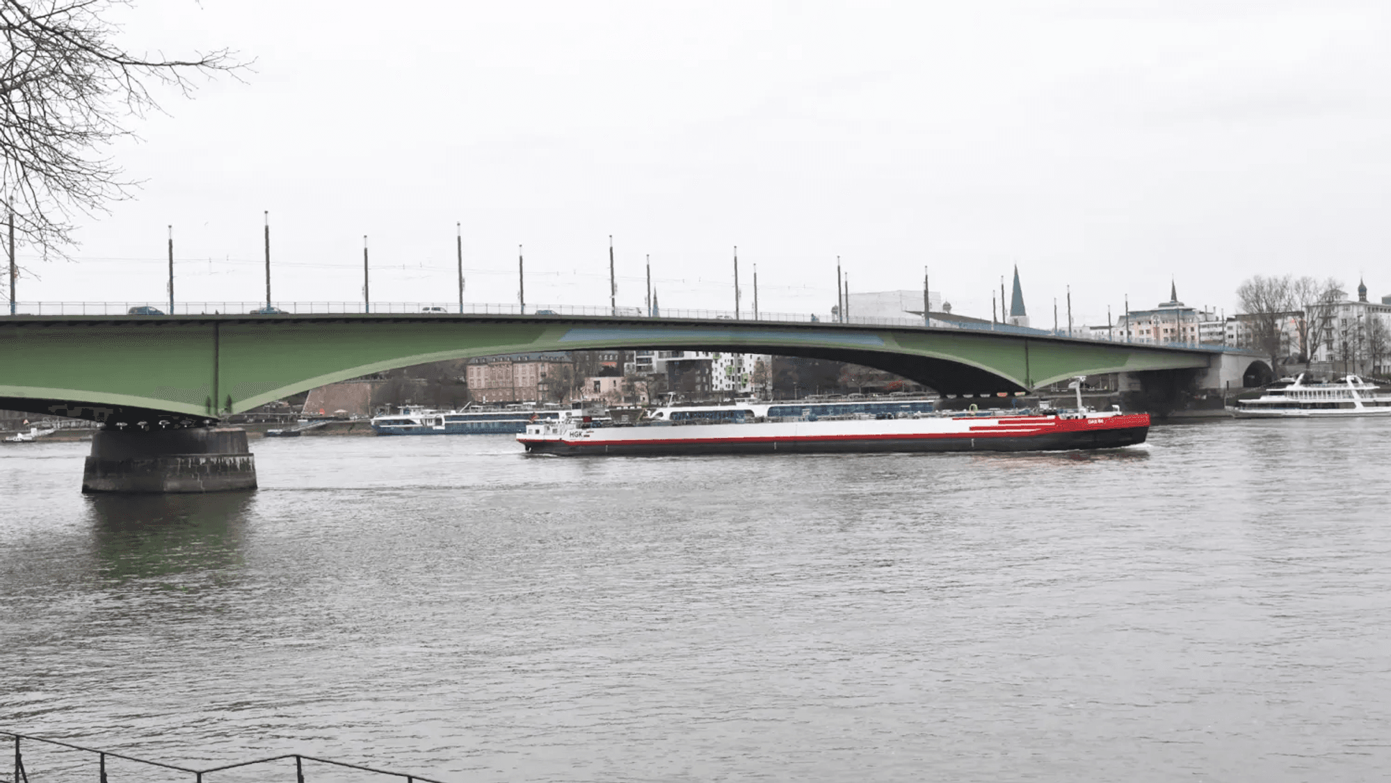 Die Kennedybrücke über den Rhein in Bonn an einem bewölkten Tag. Darunter fährt ein Schiff.