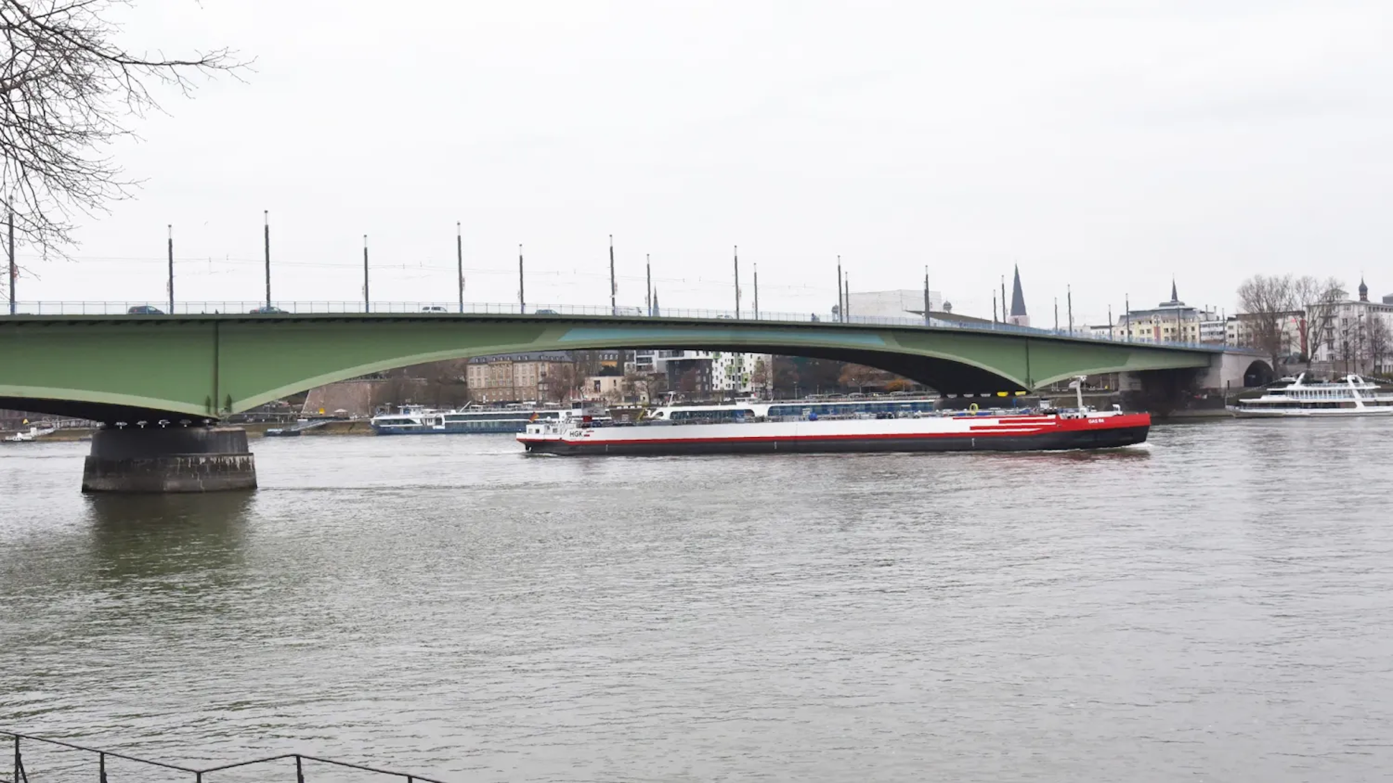 Die Kennedybrücke über den Rhein in Bonn an einem bewölkten Tag. Darunter fährt ein Schiff.