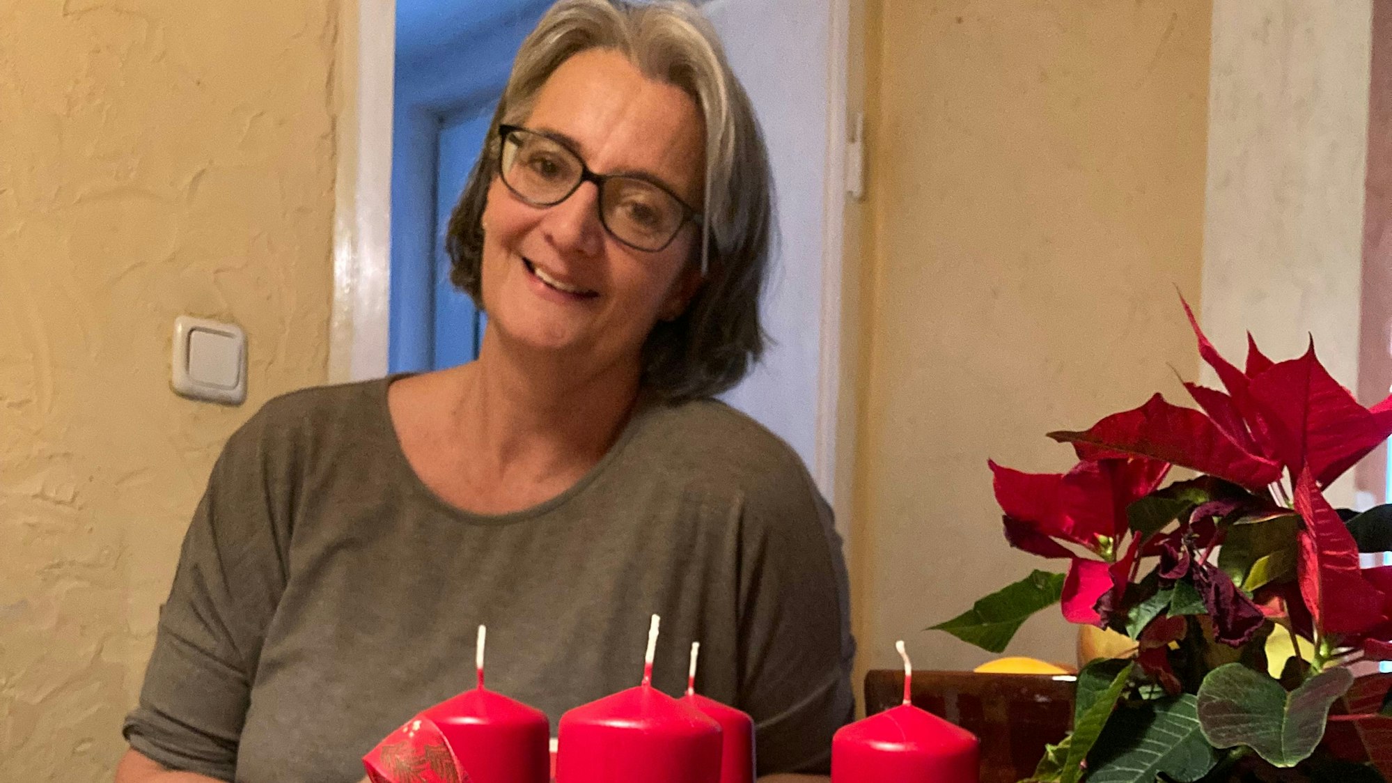 Nicole Wolke sitzt an einem Holztisch, auf dem ein Adventskranz steht.
