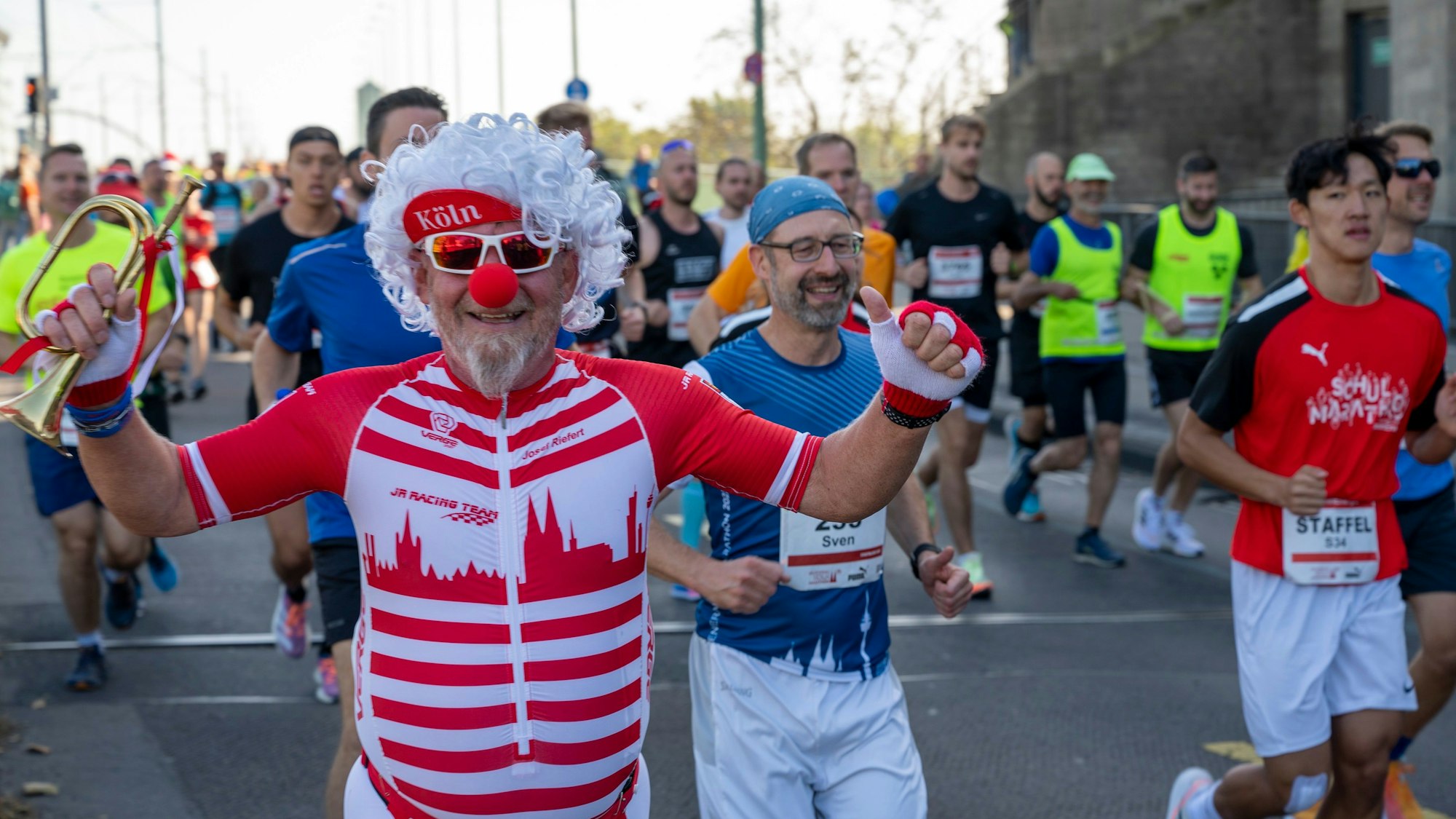 Ein kostümierter Läufer ist zu sehen: ganz in rot und weiß und mit Köln-Panorama auf der Brust.