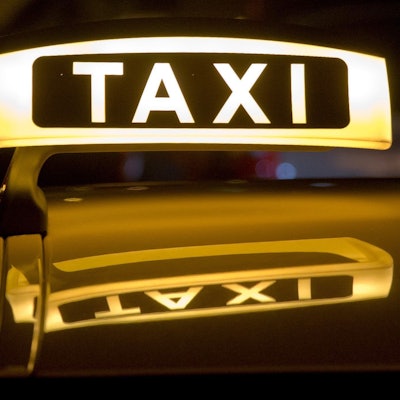 Ein Taxi steht mit leuchtendem „Taxi“-Schild für Fahrgäste bereit.