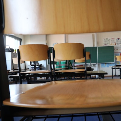 Stühle stehen auf Schultischen in einer Grundschule.