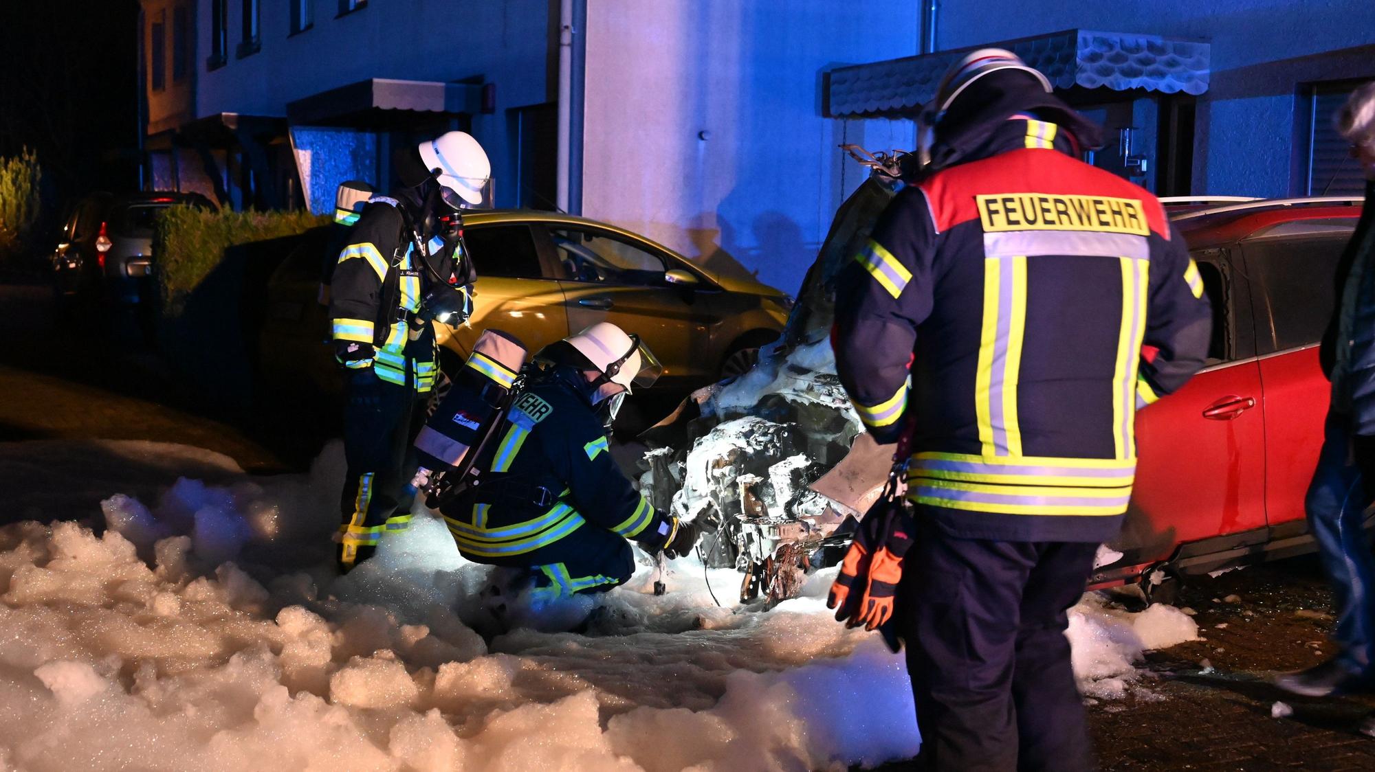 Auf dem Foto sind Feuerwehrleute vor einem ausgebrannten Pkw zu sehen.