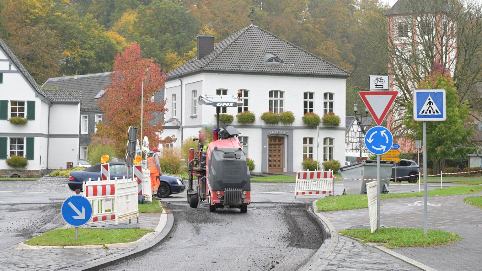 Am Kreisverkehr vor dem Odenthaler Rathaus fräst eine Baumaschine die Asphaltdecke ab.